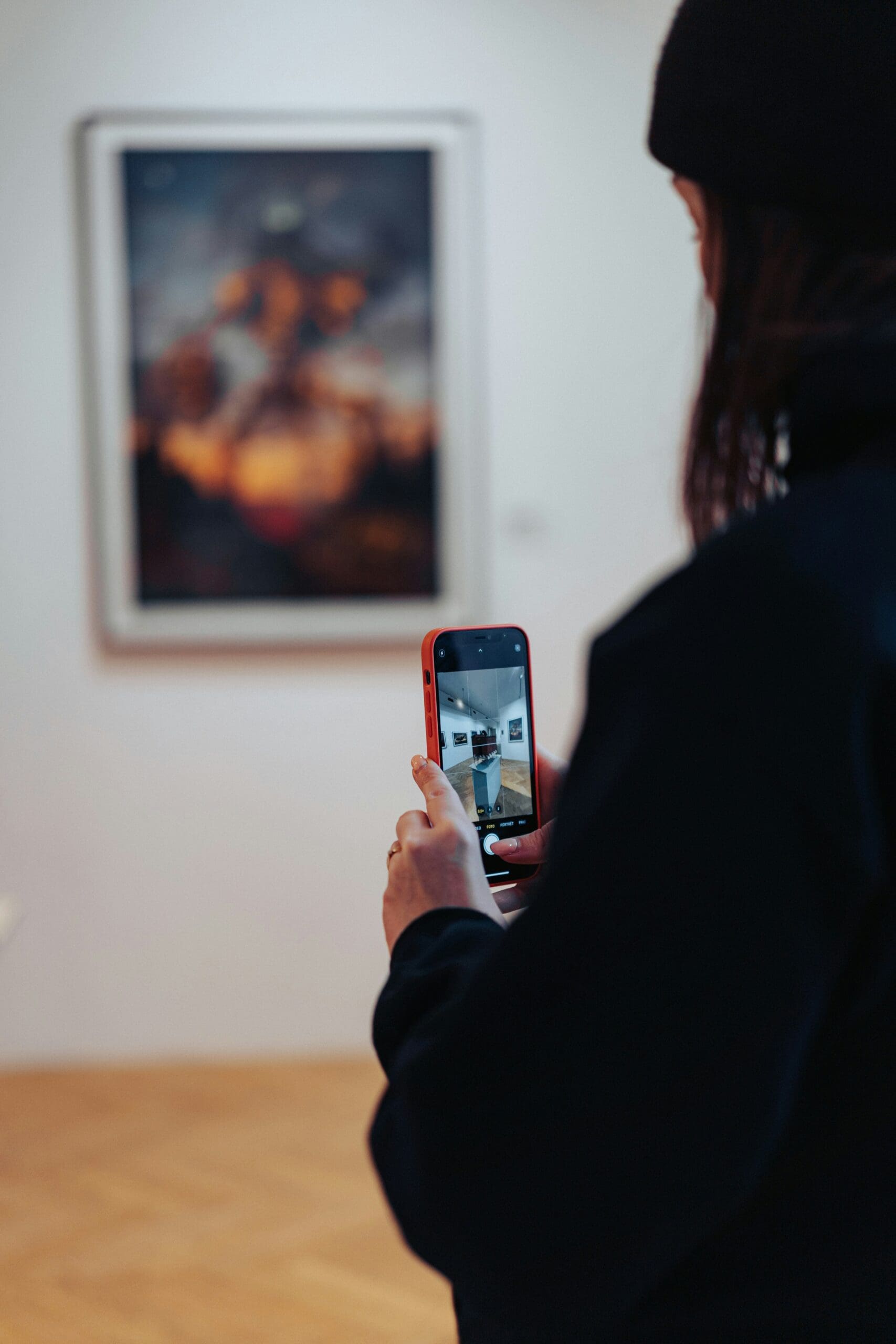 A visitor takes a photo of an exhibited artwork without flash