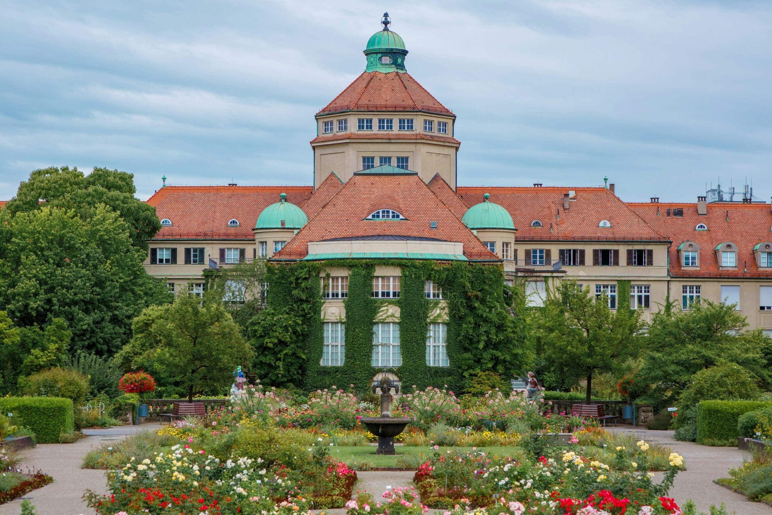 Prächtige Blumenbeete im Großen Garten mit kunstvollen Wasserspielen im Hintergrund